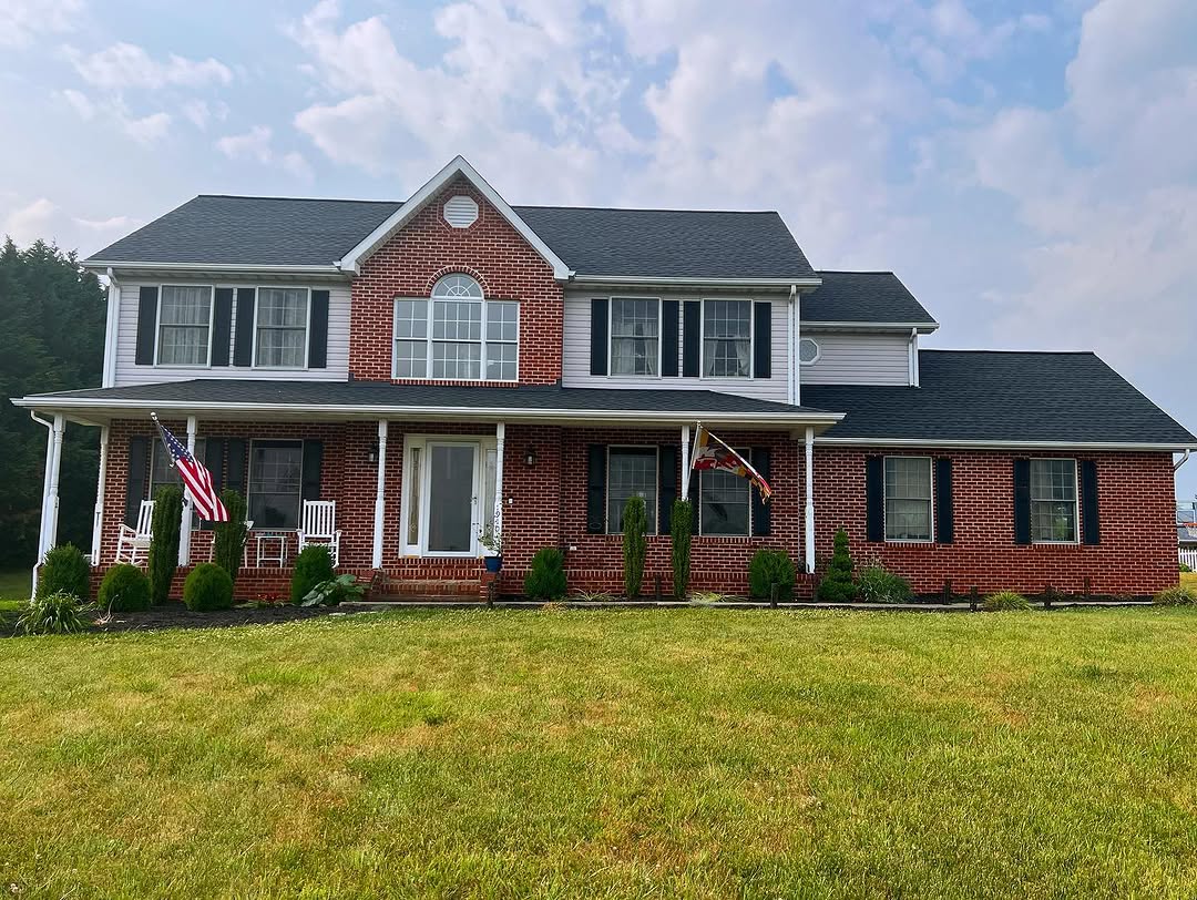 Same Maryland home after Supreme Restorations completed the full roof replacement — fresh architectural asphalt shingles installed, ridge cap finished, and the site cleaned up